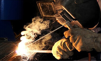 Welding smoke rising from a welding application being performed by a machine operator in a welding mask.
