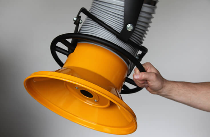 A machine operator holding onto the hood of a fume arm. An emphasis on the metal hood which offers 2x the suction distance when compared to competitors.