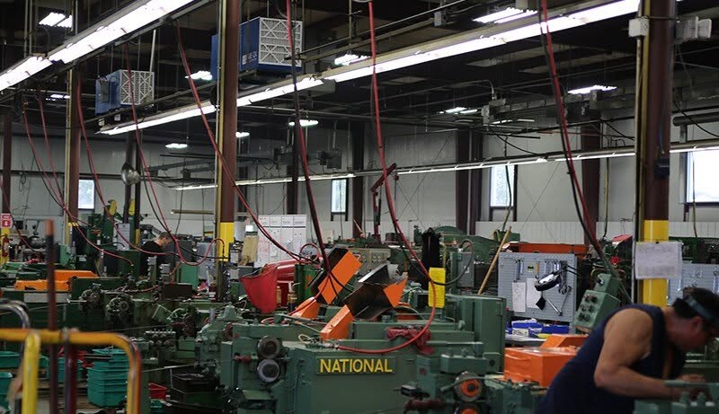 Rows of cold-header machines with OX3500C air cleaners suspended above to capture oil mist at the source
