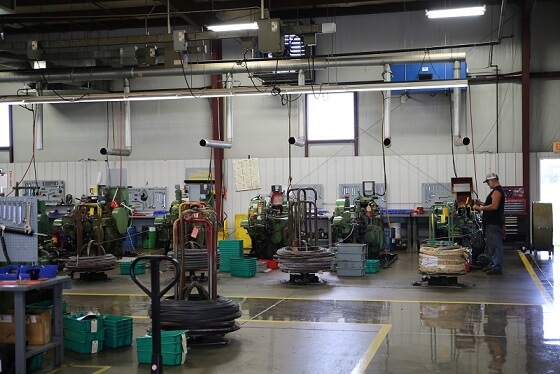 Mac Fasteners production floor with cold-header machines and overhead air cleaners for oil mist control