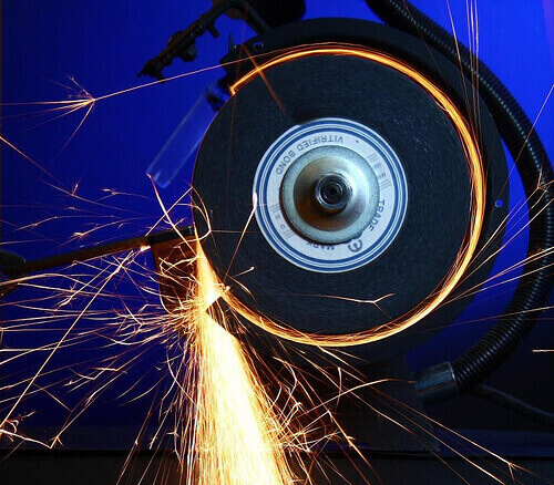 A close up of golden colored sparks being discharged while a grinding tool is in motion.