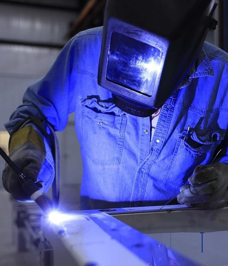 A welder wearing PPE while working on a steel metalworking project.