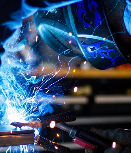 A welder working on a project while smoke and sparks are emitting around them.