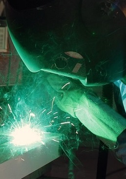Machine operator welding a steel project.