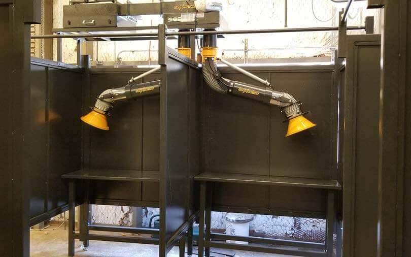 Welding booths with fume arms installed in a high school workshop to control fumes and smoke.